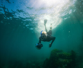 Fototapeta na wymiar Snorkelling in Japan an underwater world full of seaweed and amazing seascapes. A caucasioan man swimming underwater.