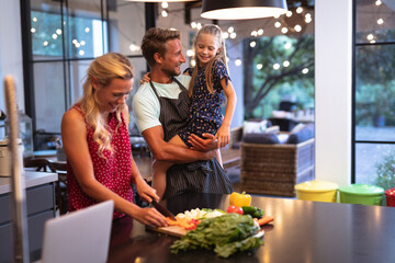 Caucasian family spending time in the kitchen and using a laptop