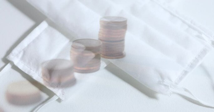 Digital composite video of stack of metallic coins against face masks in background