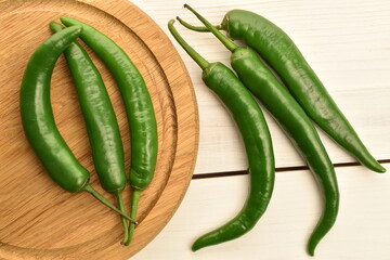Green chili pepper, close-up, on a white wooden table.