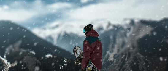 a skateboarder on top of mountains at the snow falling.