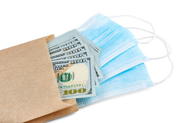 Blue medical face masks and stack of 100 USD banknotes in brown paper packet isolated on white background.