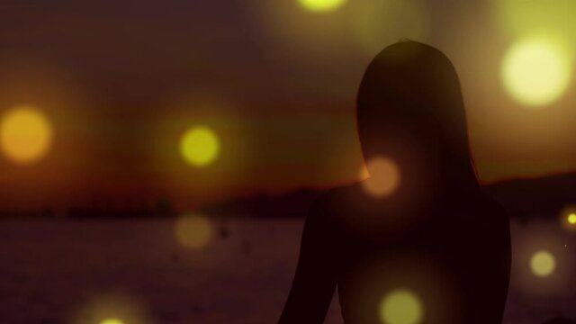 Digitally generated video of orange glowing spots moving against silhouette of woman performing yoga