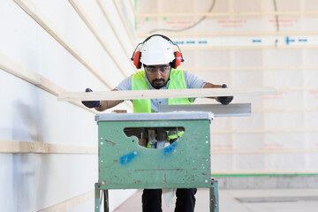 Junger Handwerker, Mann mit Helm, erstellt ein Holzgebäude