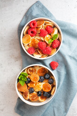 Small pancakes with blueberries, raspberries, mint and honey for a breakfast, top view