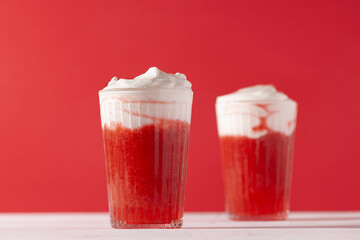 Strawberry smoothie shakes in glass with whipping cream on red background.Summer refreshing drink mocktail