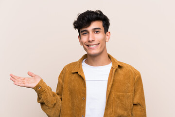 Young Argentinian man over isolated background holding copyspace imaginary on the palm to insert an...