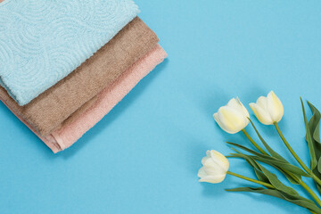 Stack of soft terry towels with flowers on a blue background.