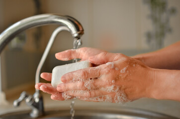 
Washing hands with soap near the tap. Water pours from the tap.