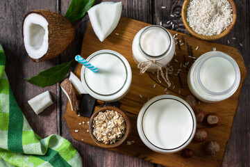 Healthy vegan food concept. Assortment of organic vegan non dairy milk from coconut, nuts, oatmeal, rice on a kitchen table. Top view flat lay background.