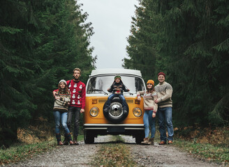 Group of young friends traveling by orange retro Bulli. Family vacation travel, holiday trip. - obrazy, fototapety, plakaty