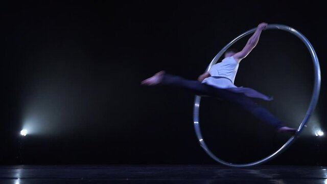 Muscular athlete doing tricks on a Cyr wheel in slow motion. Concept of control and concentration 