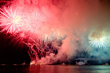 Holiday fireworks above water with reflection on the black sky background