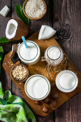 Obraz na płótnie Canvas Food and drink, health care, diet and nutrition concept. Vegan alternative nut milk from coconut, nuts, oatmeal, rice on a kitchen table. Top view flat lay background.