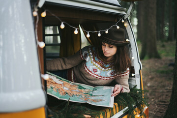 Traveler girl sitting in the retro car looking map.