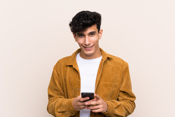 Young Argentinian man over isolated background sending a message with the mobile