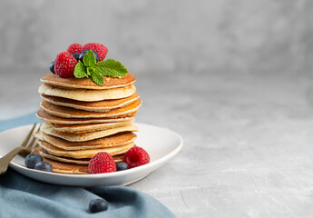 Pancakes with blueberries, raspberries, mint and honey for a breakfast