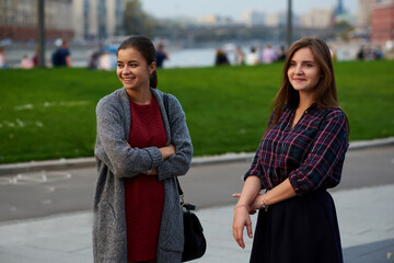 Two beautiful women tourists are standing on the street and thinking where to go on excursion during their weekend abroad. Cheerful hipster girls are resting after walking tour during spring vacation