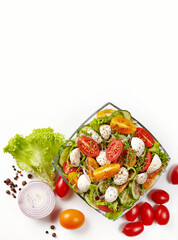 Fresh vegetable salad; sliced cucumber, red and yellow tomatoes, mozzarella cheese, caprese; onion slice, lettuce leaves and pistaches on white background. Top view. Place for text.