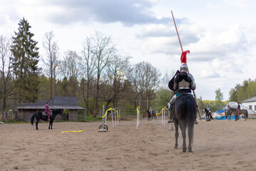 A knight in vintage armor of the 15th century rides a horse across a field for a tournament