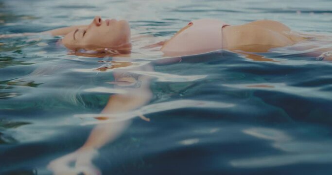 Beautiful young woman relaxing, floating in the ocean, spa wellness lifestyle