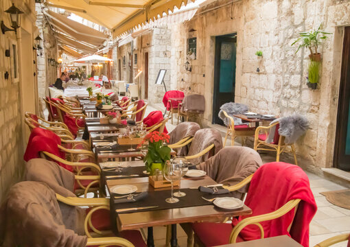 Red and beige blanket chair coverings decorate restaurant alleyway al fresco dining in Old Town Dubrovnik, Croatia