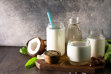 Healthy vegan food concept. Assortment of organic vegan non dairy milk from coconut, nuts, oatmeal, rice on a kitchen table. Copy space.