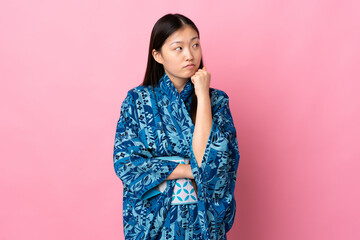 Young Chinese girl wearing kimono over isolated background with tired and bored expression