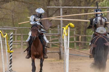 A knight in vintage armor of the 15th century rides a horse across a field for a tournament