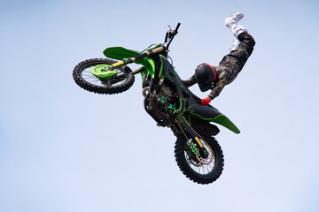 rider in protective uniform and helmet does a dangerous stunt in the air on a motorcycle. jump and...