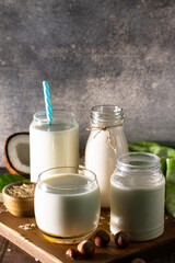 Food and drink, health care, diet and nutrition concept. Vegan alternative nut milk from coconut, nuts, oatmeal, rice on a kitchen table. Copy space.