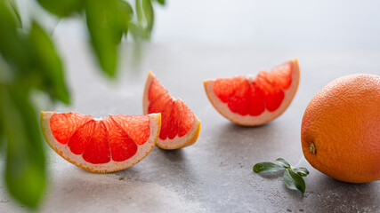 Juicy grapefruit pieces with whole fruit and green leaves on white background. close up, copy space. Superfoods, dieting, vitamins