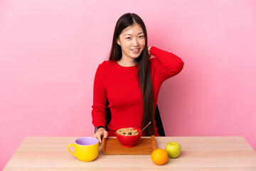 Young Chinese girl  having breakfast in a table laughing