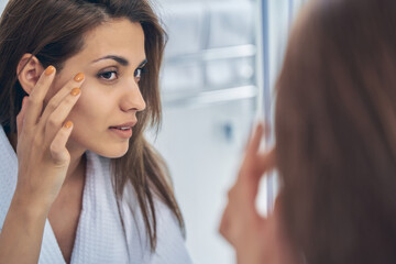 Pretty lady looking in the mirror in bathroom