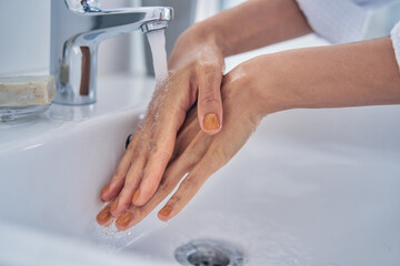 Young woman washing hands in bathroom at home