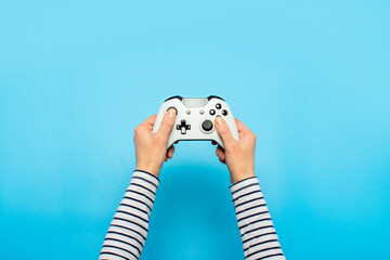 Hands holding a gamepad on a blue background. Banner. Concept games, video games © Alex