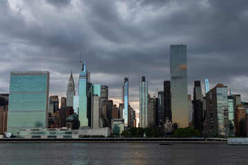 Naklejka premium Ciemne i złowieszcze niebo z panoramą Midtown Manhattan podczas zachodu słońca nad East River w Nowym Jorku