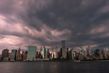 Naklejka premium Dark and Ominous Sky with the Midtown Manhattan Skyline during a Sunset along the East River in New York City