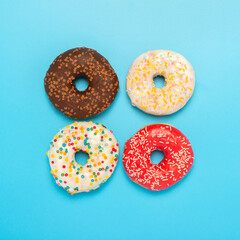 Tasty donuts of different types on a blue background. Concept of sweets, bakery, pastries. Square. Flat lay, top view