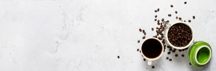 cup with coffee, a can of coffee beans and coffee beans are scattered on a concrete background. Banner. Concept of fresh coffee, breakfast, plantation. Top view, flat lay