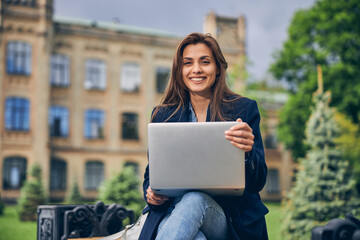 Attractive lady sitting alone outdoors with computer