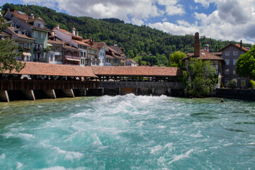 Fototapeta na wymiar view of the turbulent river flow at the dam and beautiful houses near the coast in Switzerland in Thun