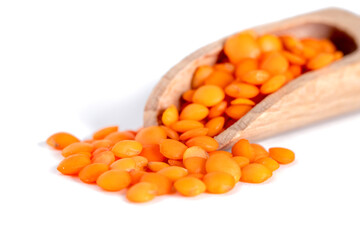 Red lentils in the wooden spoon, isolated on white background, macro shot