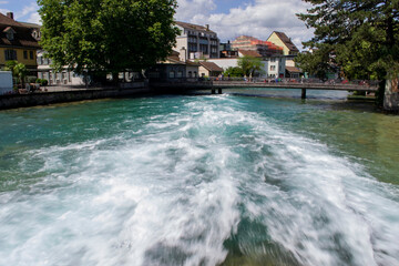 view of the turbulent river flow at the dam and beautiful houses near the coast in Switzerland in Thun