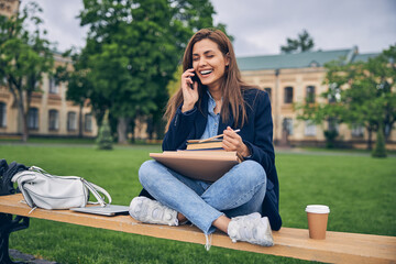 Beautiful young lady with dark hair spending time outdoors near university