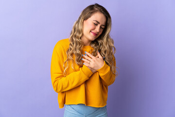 Young Brazilian woman isolated on purple background having a pain in the heart
