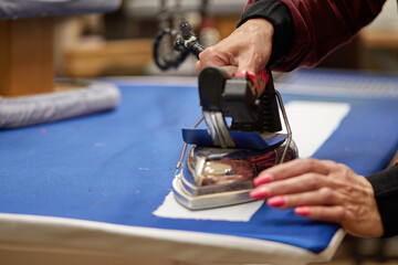 Tailor ironing the fabric. seamstress irons dress in a sewing workshop