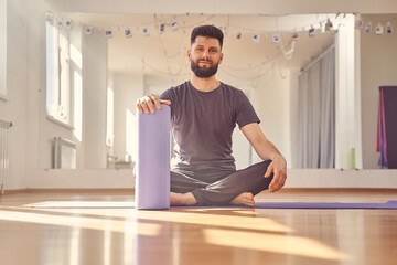 Handsome young man sitting on the floor in yoga studio