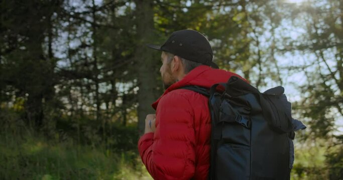 Modern urban nomad travel blogger or adventurer walk through forest. Hiking and camping with minimal gear or location searching for photoshoot. Outdoors camper lifestyle vibes