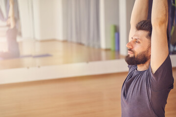 Handsome young man doing yoga exercise in studio